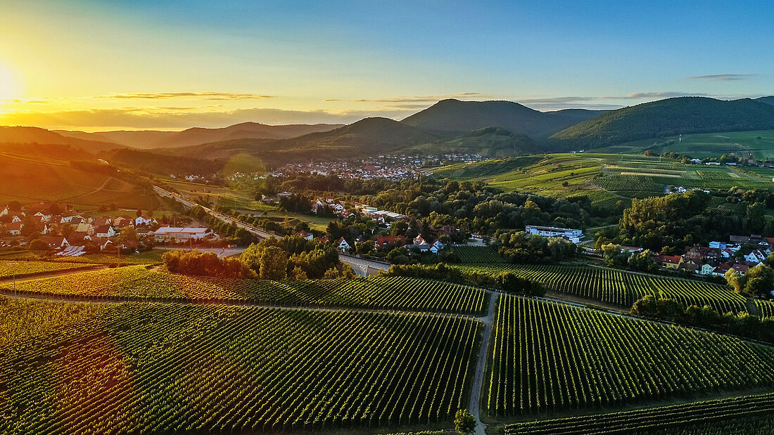 Landschaft bei Sonnenuntergang, Häuser und Straßen im Hintergrund