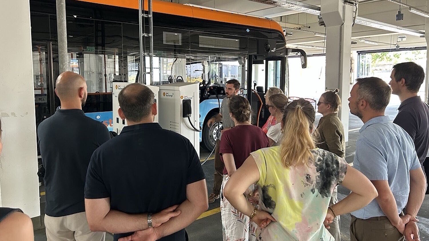 Personen besichtigen den Betriebshof der rnv in dem ein BZ-REX-Bus an einer Ladesäule steht
