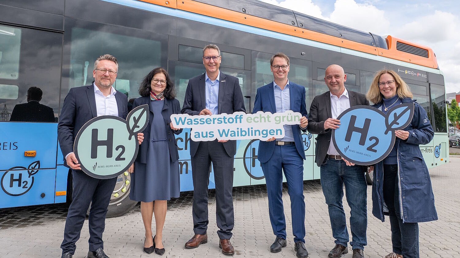 Landrat und Oberbürgermeister posieren mit weiteren Verantwortlichen vor zwei Wasserstoffbussen