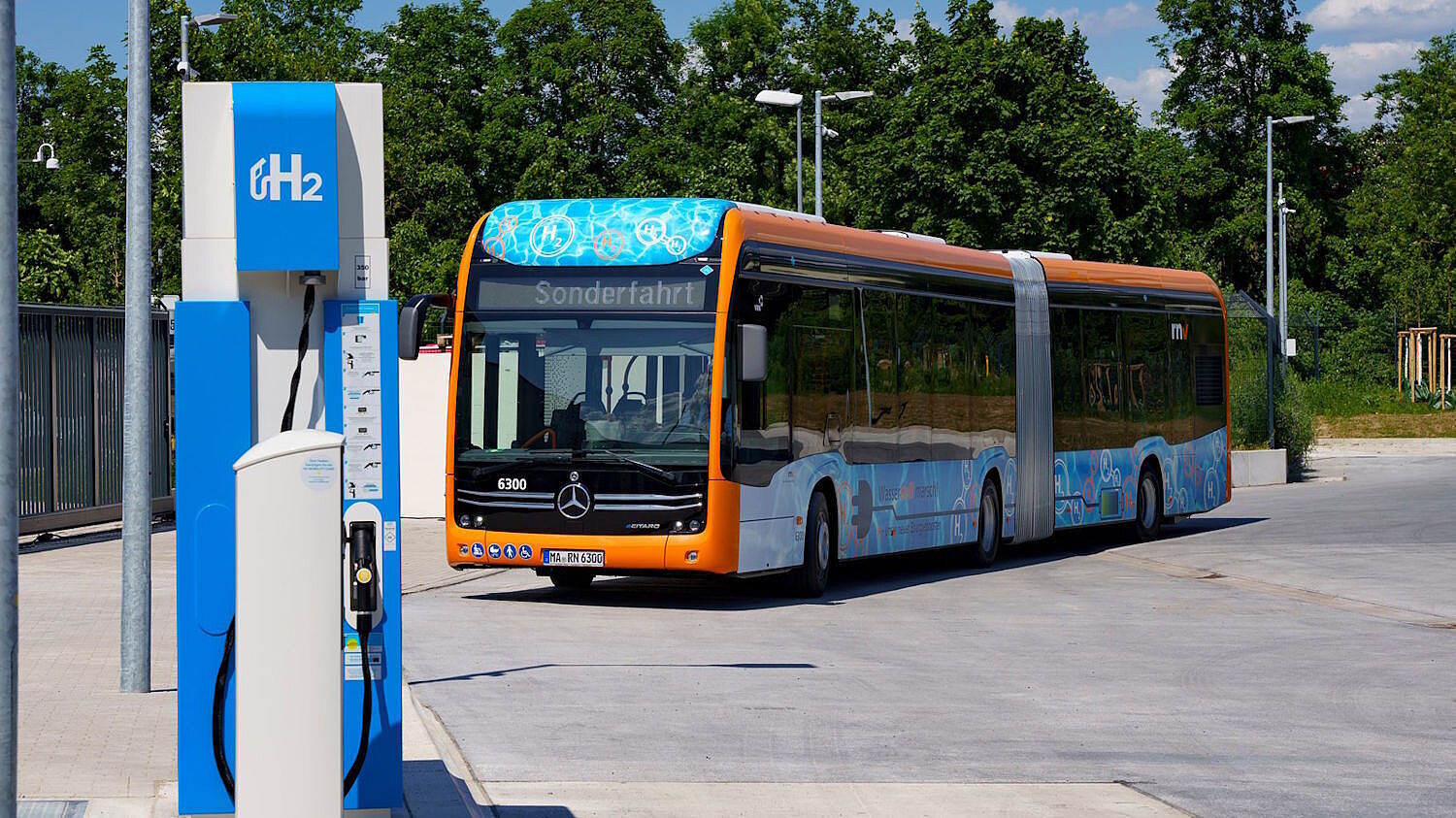Ein Gelenkbus mit Brennstoffzellenantrieb fährt an eine Wasserstofftankstelle.